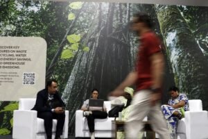 COP17 da Biodiversidade: pessoas sentadas em sofás diante de painel de floresta em conferência da ONU.