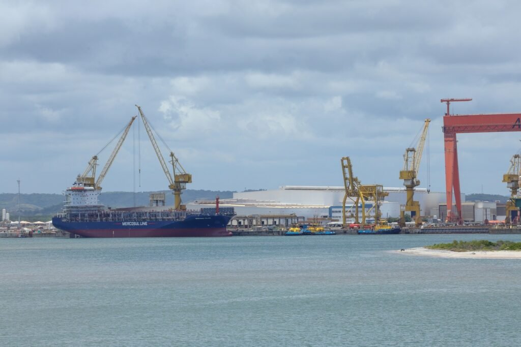 acordo Mercosul-EFTA: Navio de carga da Mercosul Line atracado em porto industrial sob céu nublado.