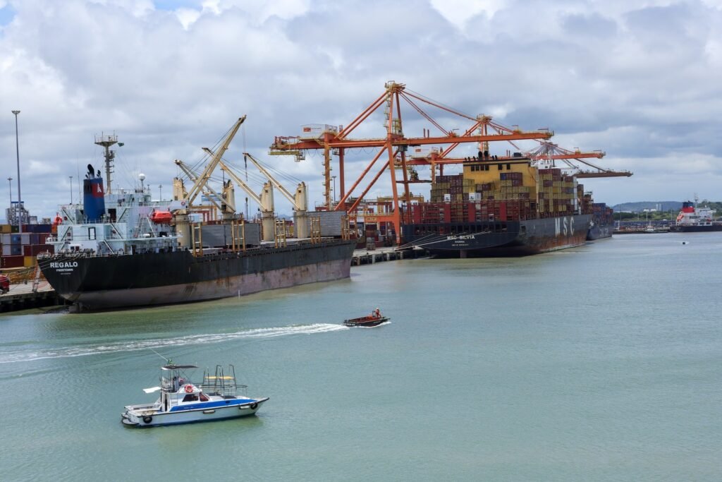 crédito extraordinário: Vista aérea de navios de carga atracados no Porto de Suape com guindastes ao fundo.