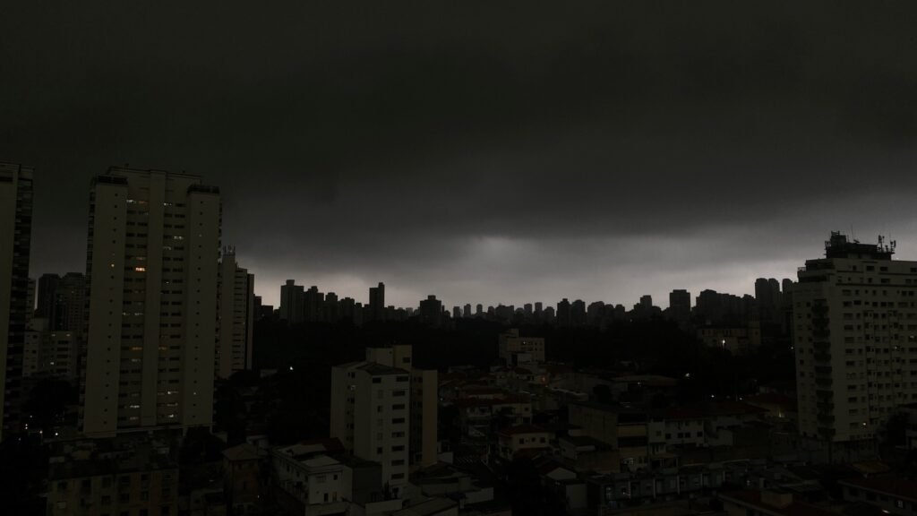 Previsão de chuvas: cidade sob céu escuro e nublado, sugerindo temporal com prédios sob nuvens densas.