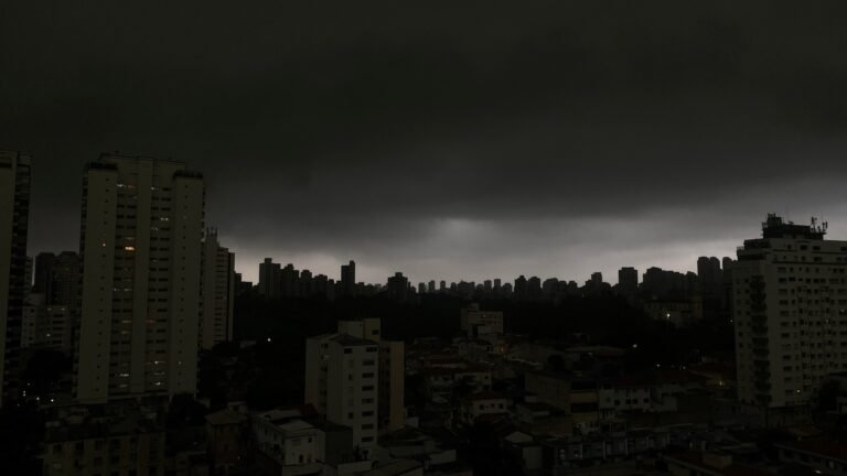 Chuvas fortes predominam nas regiões Sudeste e Centro-Oeste do país 7 Previsão de chuvas: cidade sob céu escuro e nublado, sugerindo temporal com prédios sob nuvens densas.