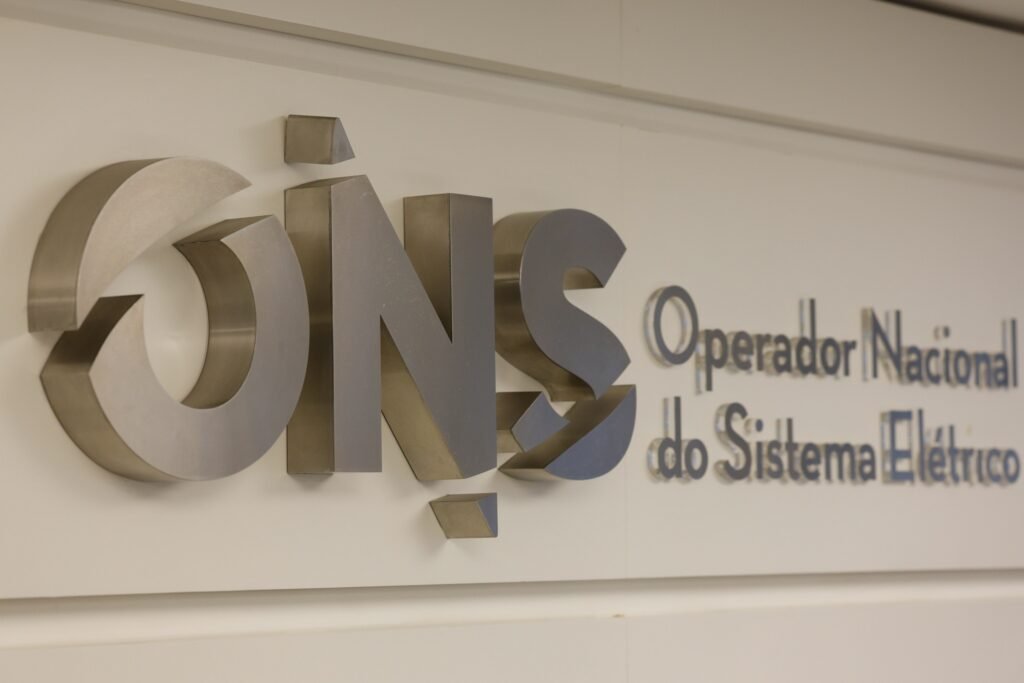 segundo turno: Logotipo metálico do Operador Nacional do Sistema Elétrico (ONS) fixado em parede branca.