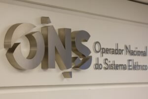 segundo turno: Logotipo metálico do Operador Nacional do Sistema Elétrico (ONS) fixado em parede branca.