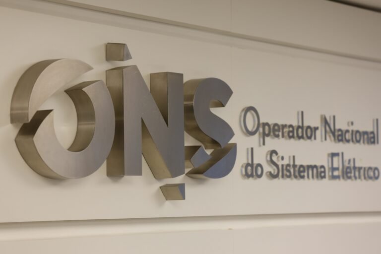 ONS fará operação especial para garantir energia no segundo turno 4 segundo turno: Logotipo metálico do Operador Nacional do Sistema Elétrico (ONS) fixado em parede branca.