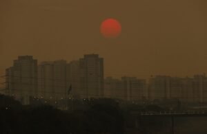 meta climatica: Prédios de São Paulo sob céu amarronzado por poluição com sol vermelho ao fundo.