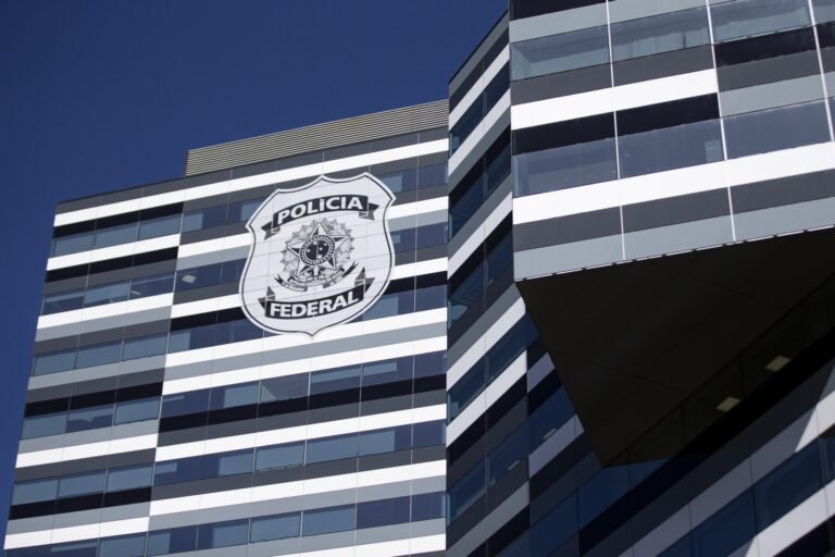 operação da Força Nacional: Fachada de prédio moderno com faixas horizontais brancas e escuras, exibindo o logotipo da Polícia Federal.