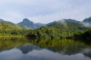 reserva ambiental: Montanhas cobertas por floresta densa refletidas em um lago calmo na Região Serrana do Rio de Janeiro.