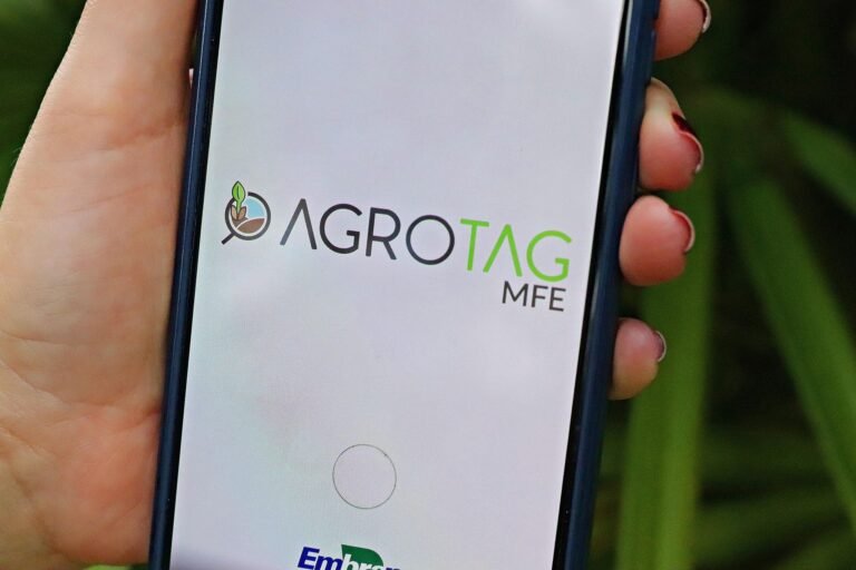 efeito estufa: Mão segurando smartphone com o logotipo Agrotag MFE da Embrapa.