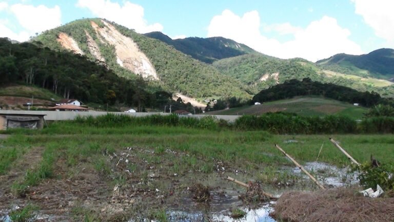 Super-ricos geram mais poluição e lucram com desastres climáticos 4 desastres climáticos: paisagem de montanhas com deslizamentos de terra e solo alagado em Nova Friburgo.