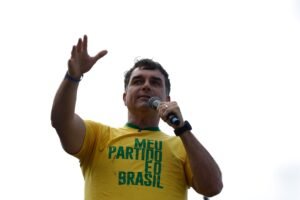 agendas de campanha: Flávio Bolsonaro discursa ao microfone com a mão erguida em evento político.