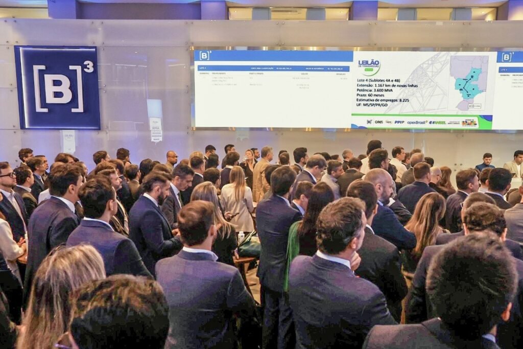 leilões de transmissão: Profissionais observam painel digital na B3 com dados sobre leilão de energia da Aneel.